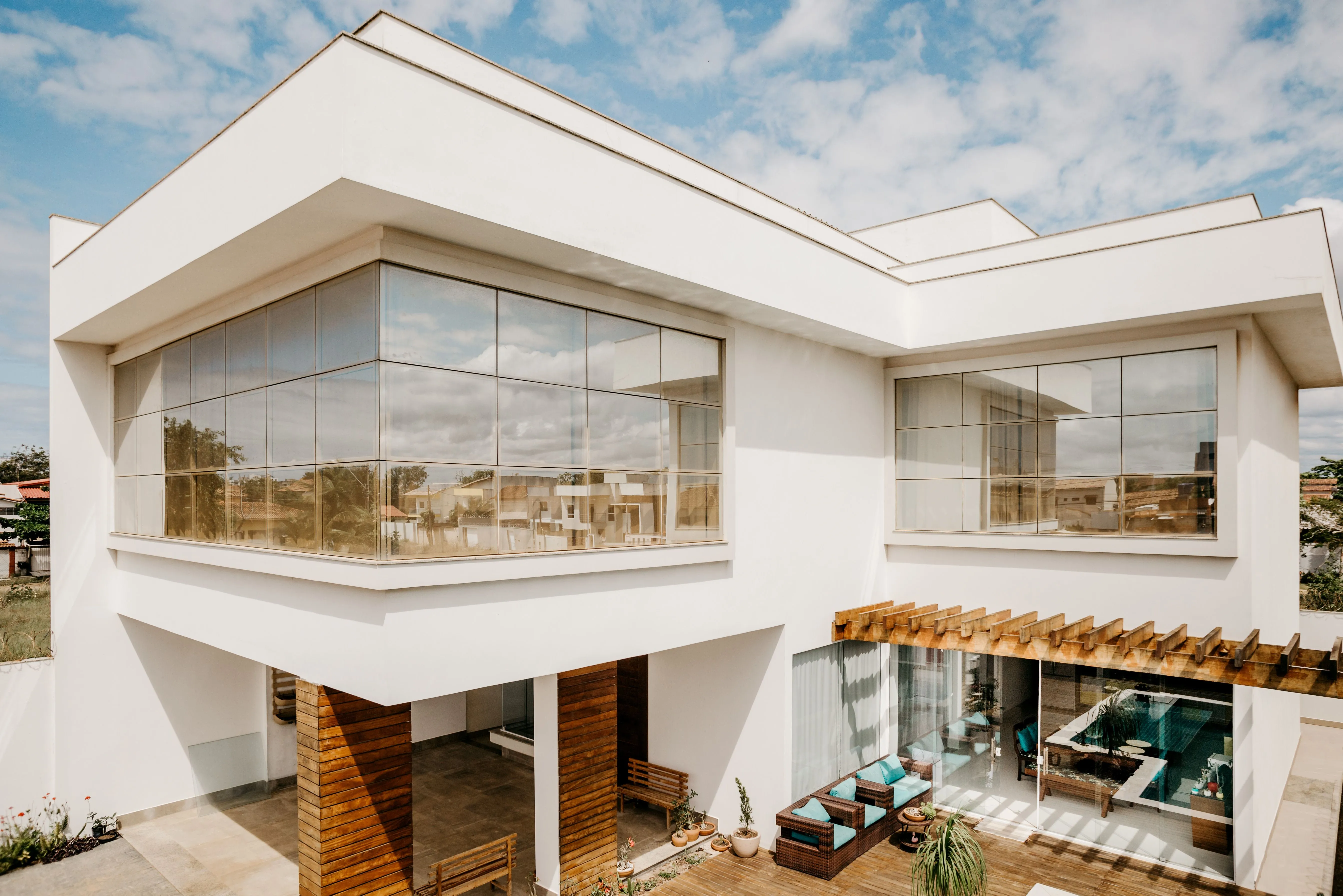 Stylish contemporary house exterior with large windows and wooden details under a blue sky.